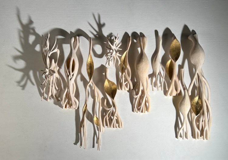 Picture of two astrocyte-sculptures and eight purkinje-sculptures. They are in white aspen wood with details in gold.